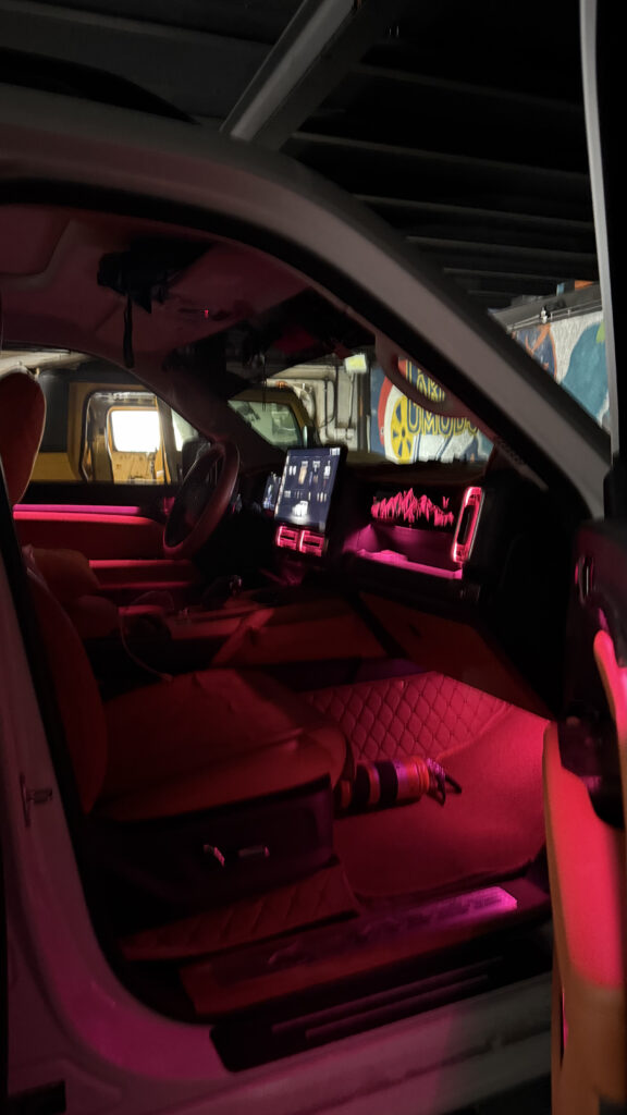Luxury SUV interior featuring vibrant pink RGB ambient lighting on the dashboard, door panels, footwell, and centre console for a premium driving experience.